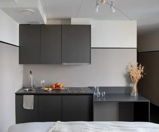 a kitchen with black cabinets and a white bed