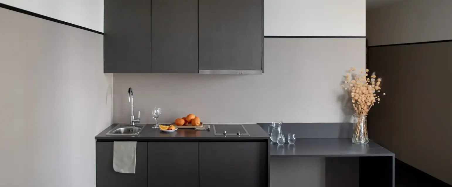a kitchen with black cabinets and a white bed