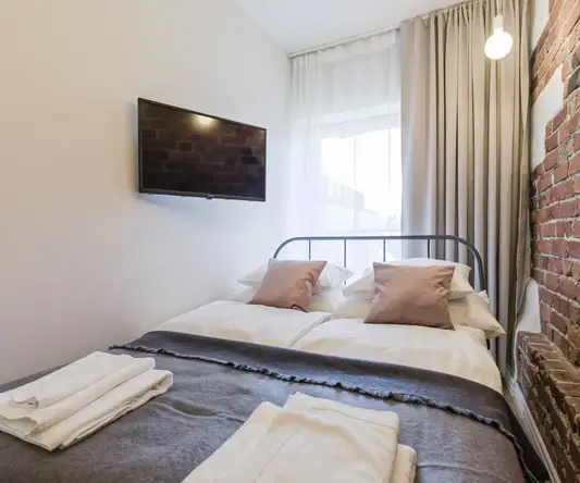 a bed with pillows and a tv on the wall