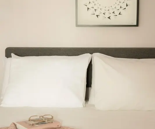 a bed with white pillows and a pink book on it