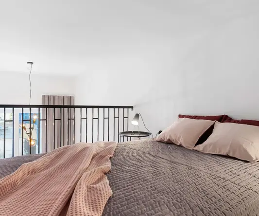 a bed with pillows and a lamp on a balcony