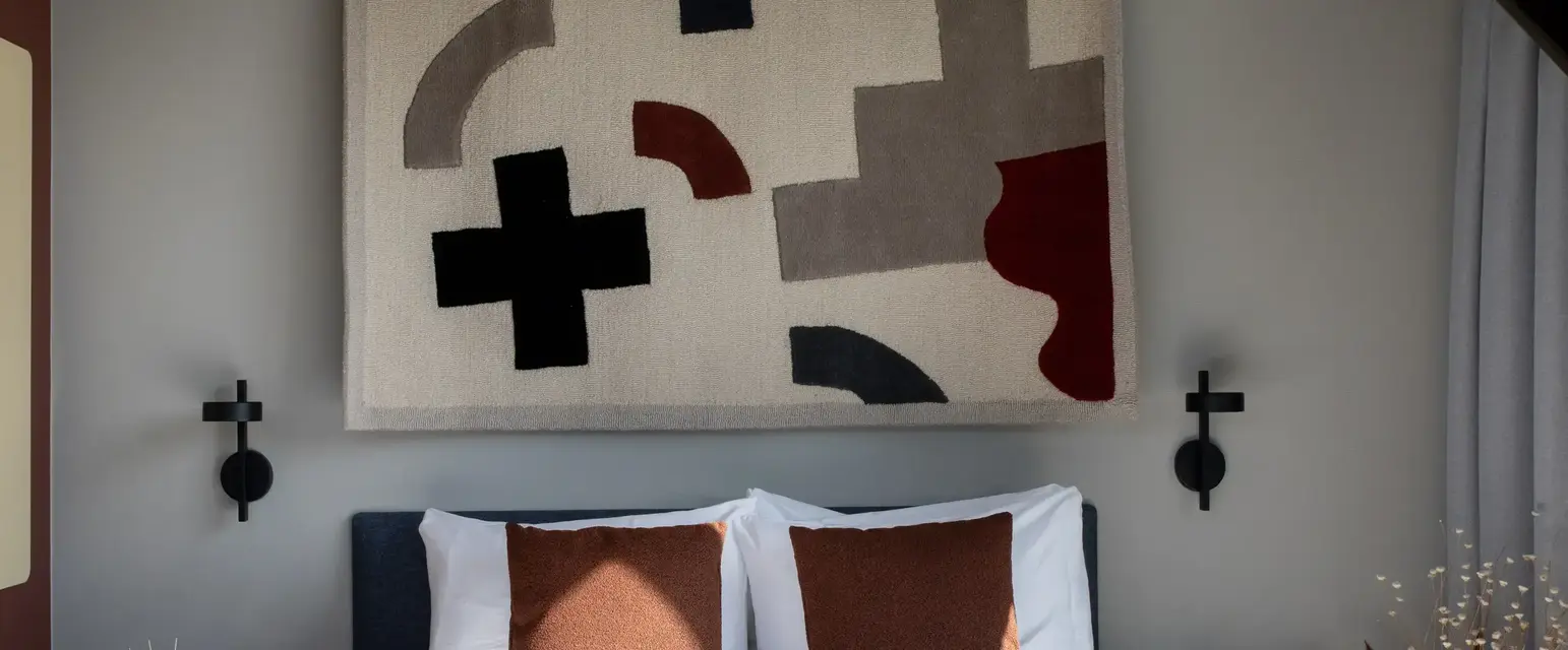 a bed with pillows and a rug above it
