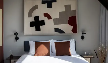 a bed with pillows and a rug above it