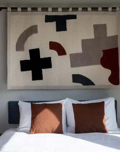 a bed with pillows and a rug above it