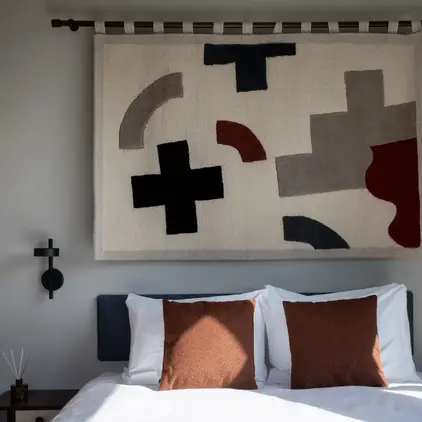 a bed with pillows and a rug above it