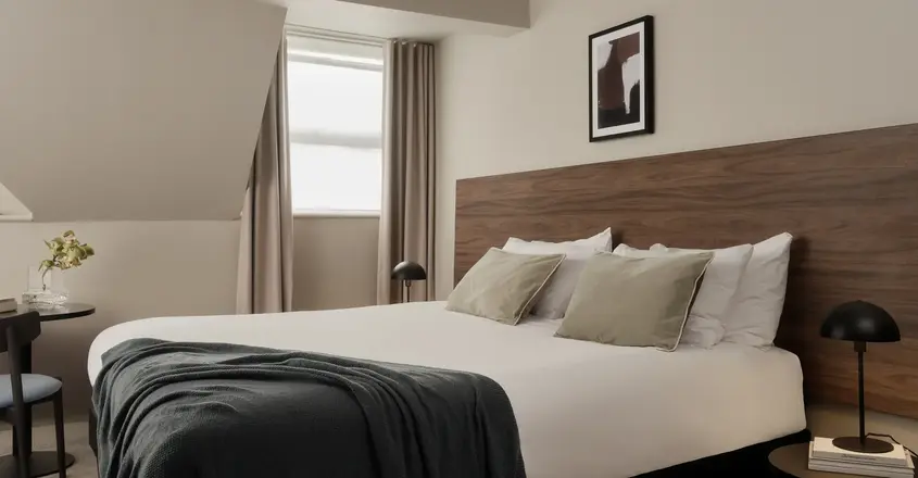a bed with a black blanket and a wood headboard