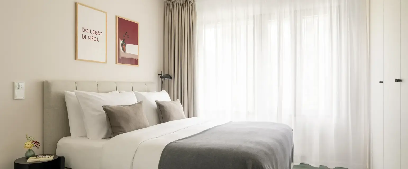 a bed with pillows and a lamp in a room with curtains
