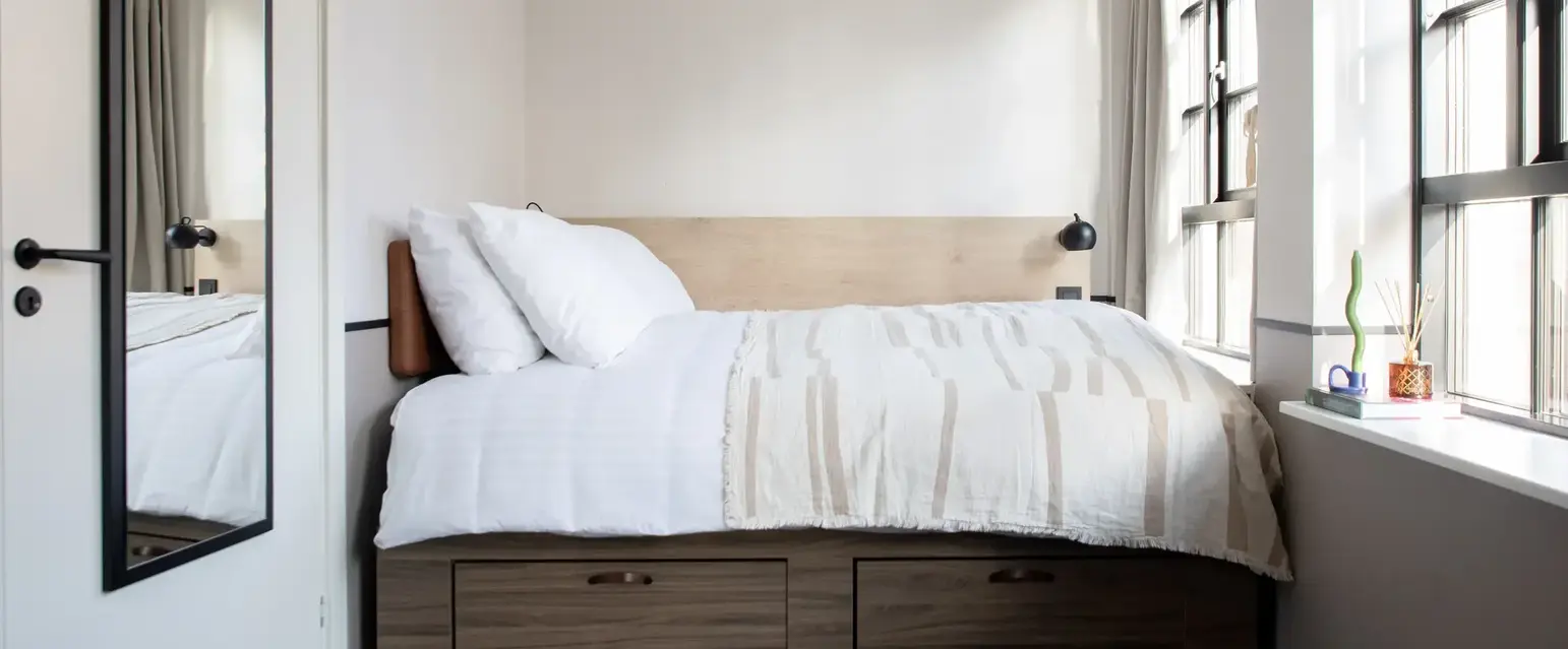 a bed with white sheets and pillows