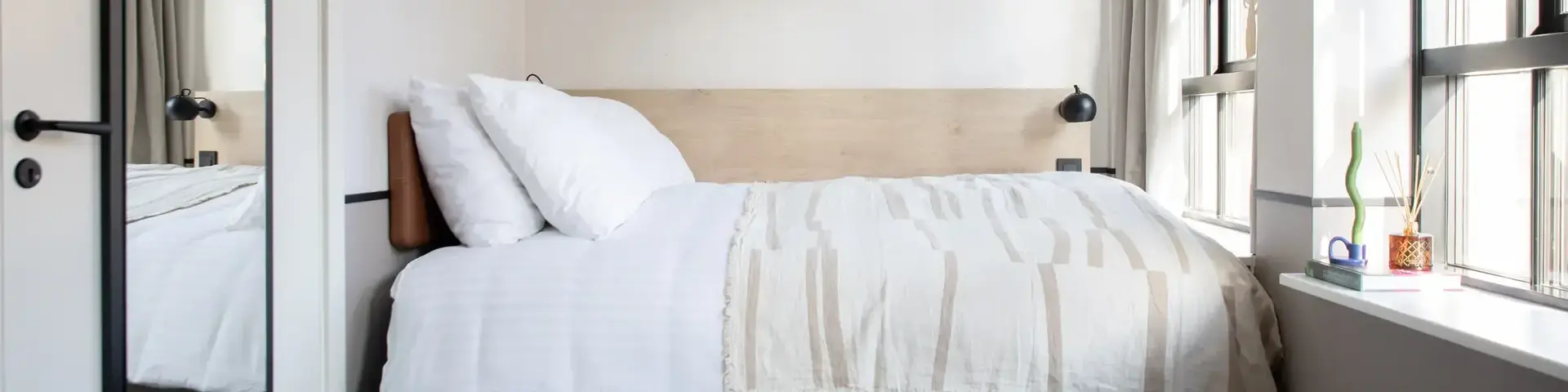 a bed with white sheets and pillows