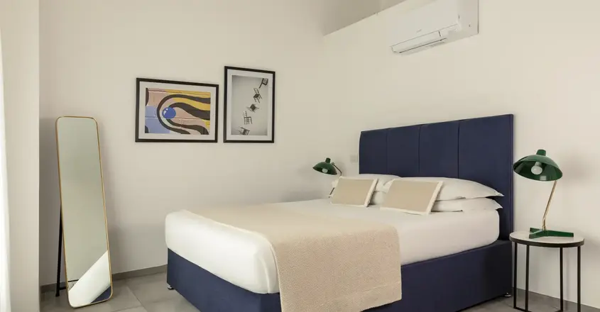 a bed with a blue headboard and a mirror