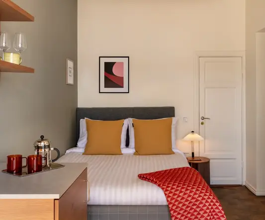 a bed with a red blanket and a lamp in a room