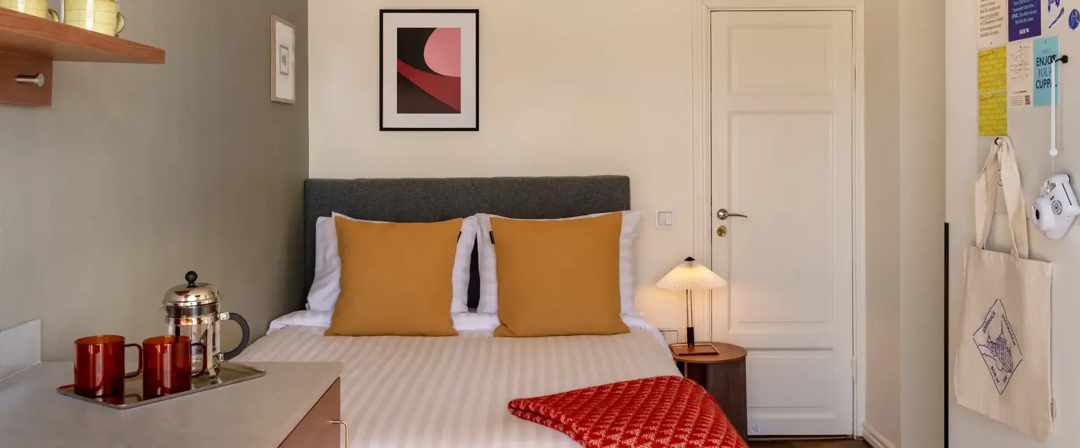 a bed with a red blanket and a lamp in a room