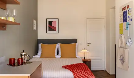 a bed with a red blanket and a lamp in a room