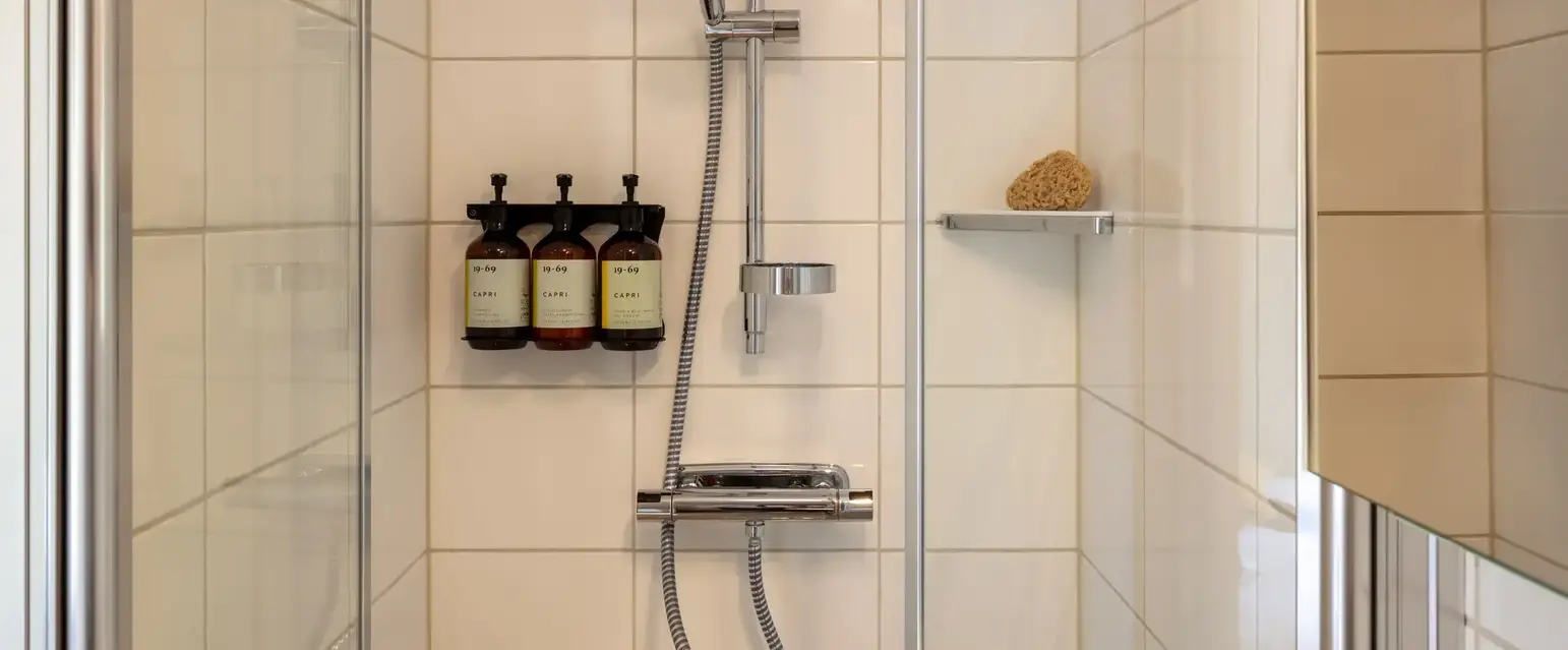 a shower with a shower head and a shelf