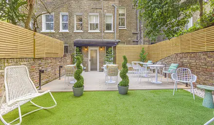 a patio area with chairs and tables in front of a brick building