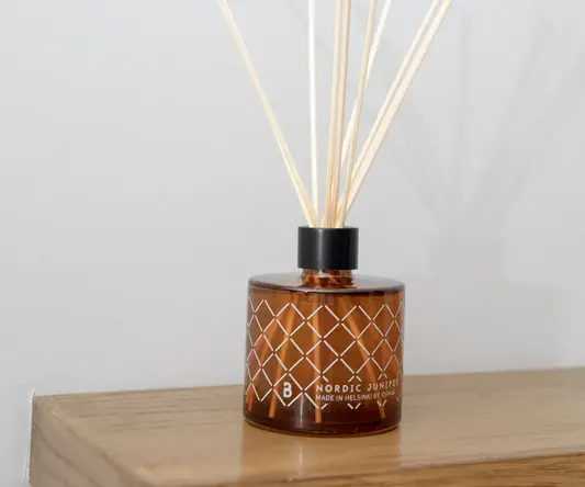 a brown glass container with sticks in it