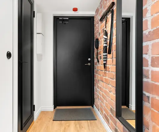 a hallway with a brick wall and a black door