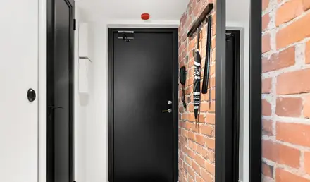 a hallway with a brick wall and a black door