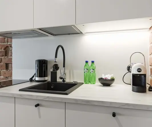 a kitchen counter with a sink and bottles