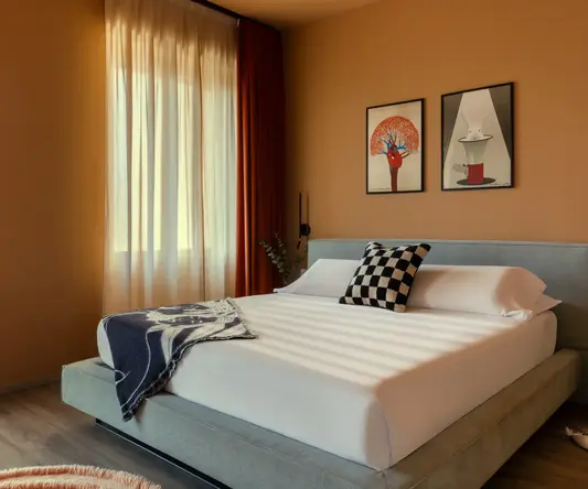 a bed with pillows and a rug in a room with a window