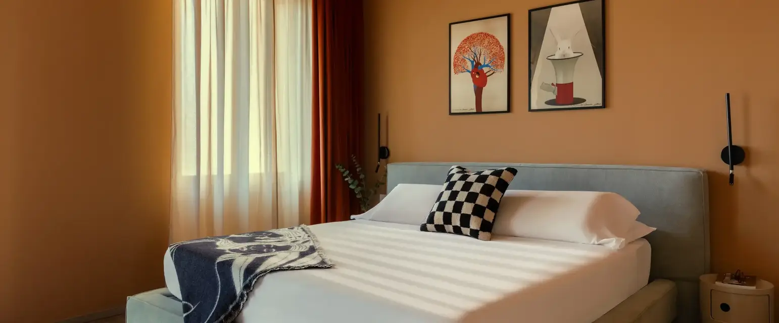 a bed with pillows and a rug in a room with a window