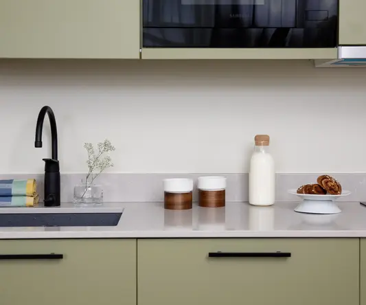 a kitchen counter with a microwave and a black faucet