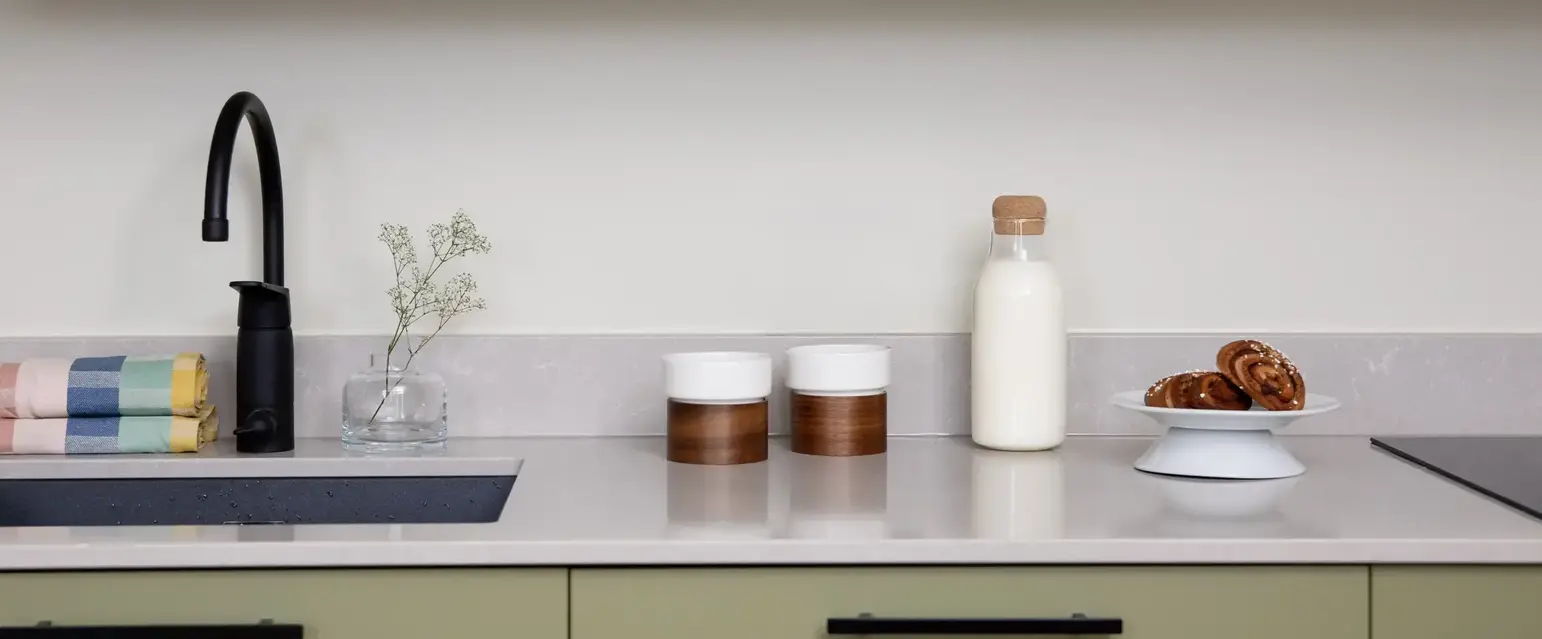 a kitchen counter with a microwave and a black faucet
