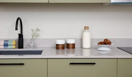 a kitchen counter with a microwave and a black faucet