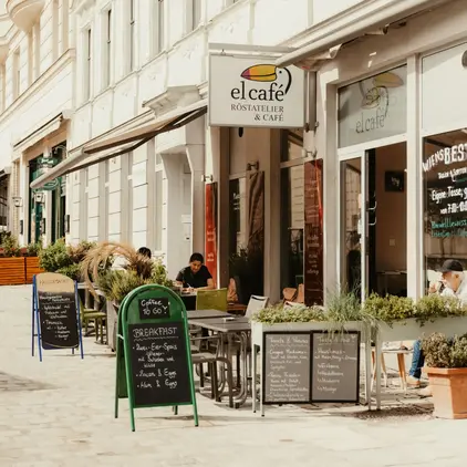 a sidewalk with tables and chairs outside of a restaurant