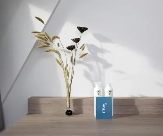 a vase with dried flowers and a bottle on a table