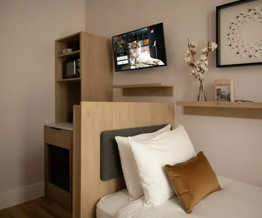 a bed with pillows and a tv on the wall