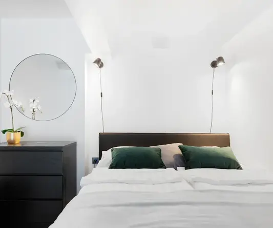 a bed with green pillows and a dresser