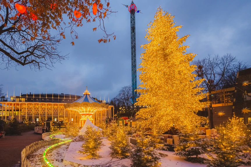 A golden lit Christmas tree in Tivoli Gardens, Copenhagen, at dusk