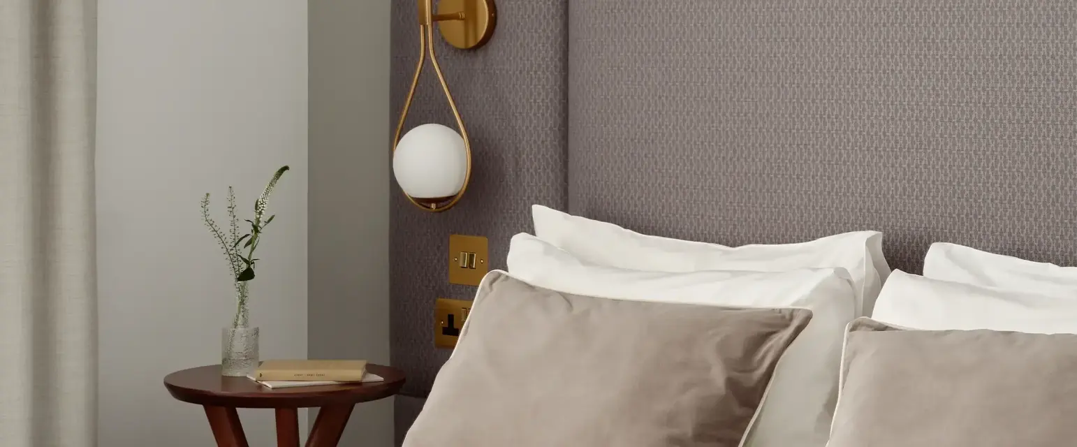 a bed with pillows and a table with a plant on it