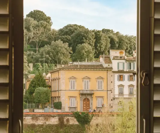 a window with a yellow building and trees in the background