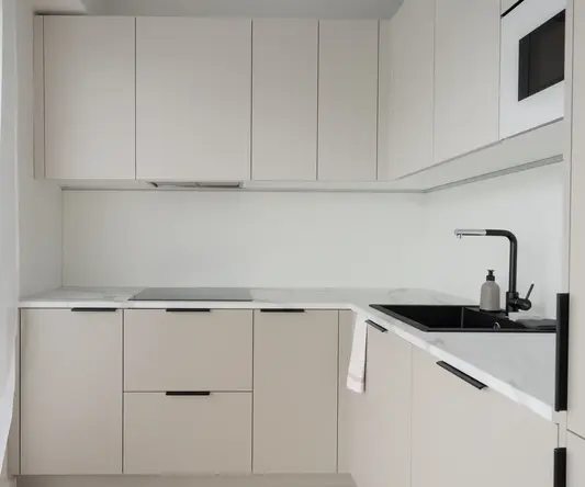a kitchen with white cabinets and black handles