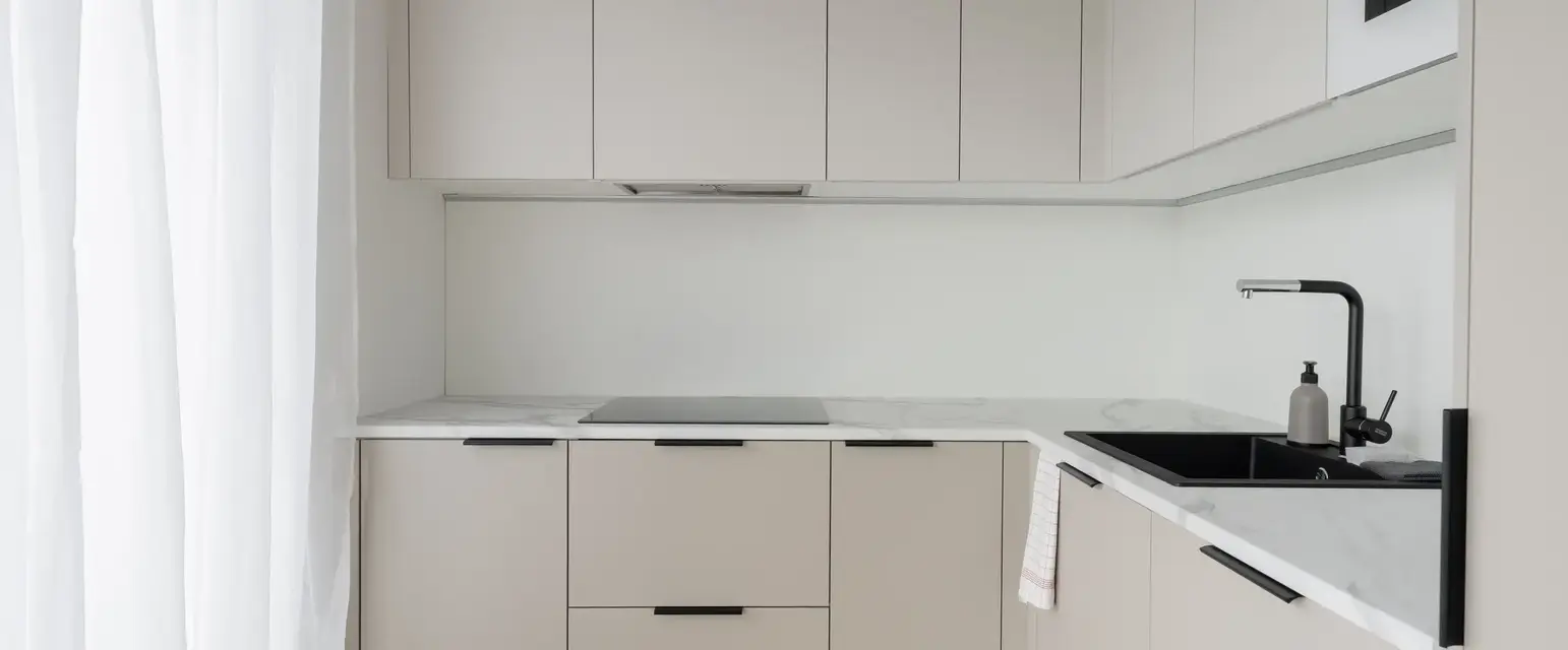 a kitchen with white cabinets and black handles
