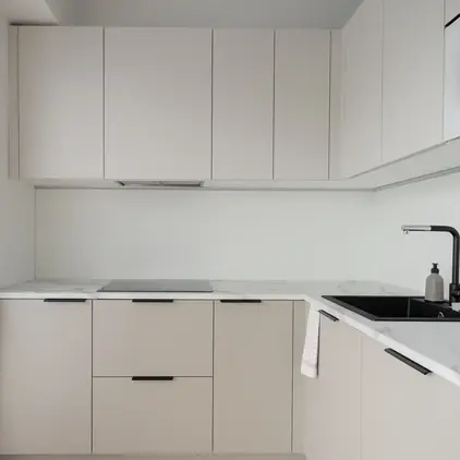 a kitchen with white cabinets and black handles