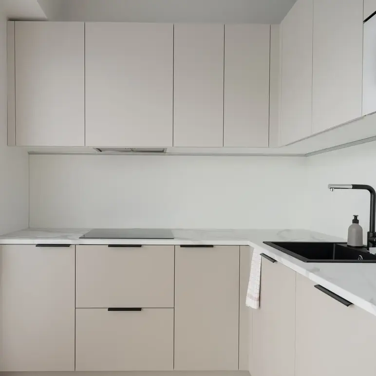a kitchen with white cabinets and black handles