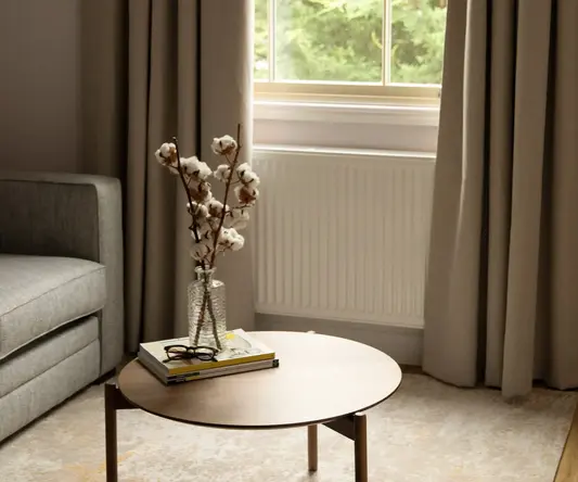 a table with a vase of cotton flowers on it