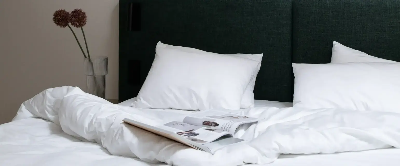 a bed with white sheets and a book on it