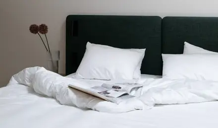 a bed with white sheets and a book on it