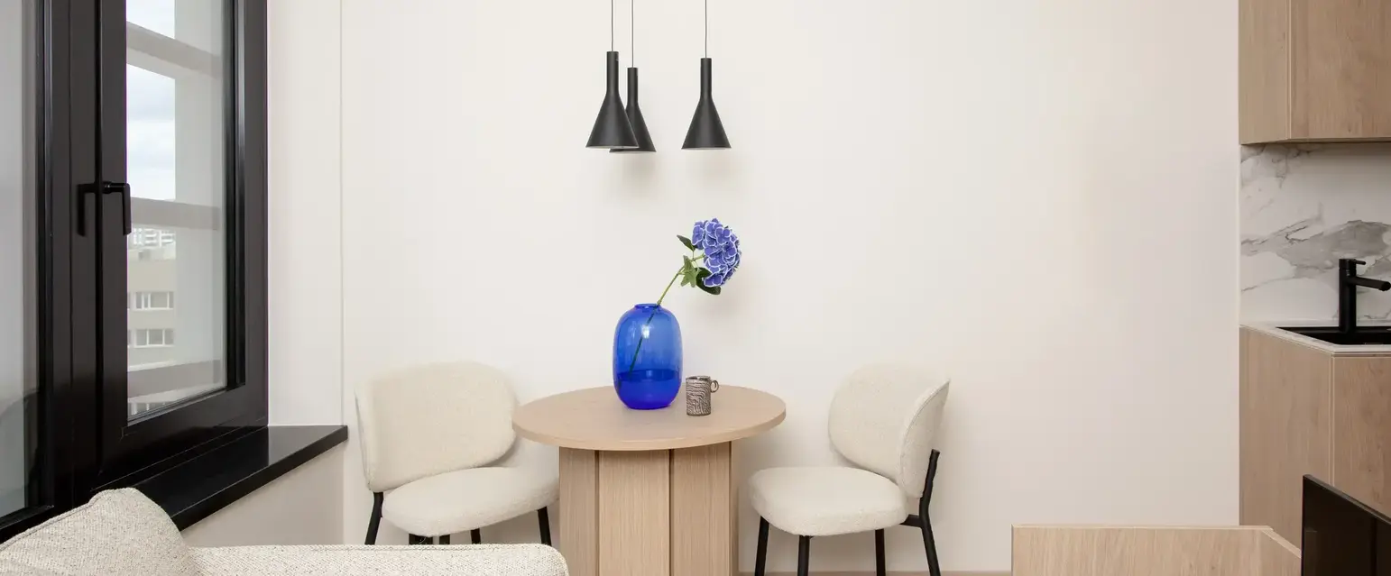 a table with chairs and a vase of flowers