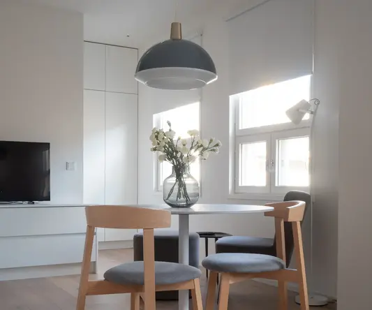 a table with chairs and a vase of flowers in it