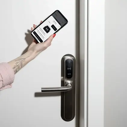 a hand holding a phone next to a door handle