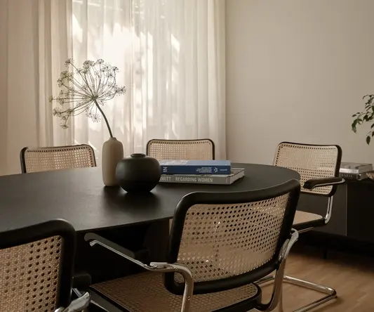 a table with chairs and a vase on it