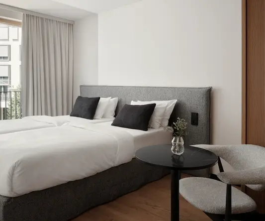 a bed with white sheets and black pillows in a room