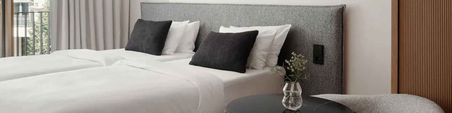 a bed with white sheets and black pillows in a room
