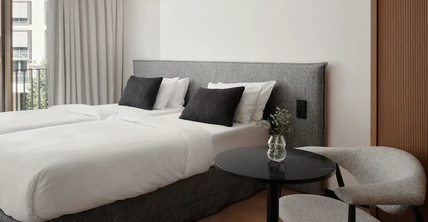 a bed with white sheets and black pillows in a room