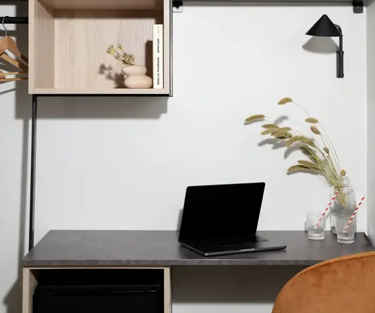 a desk with a laptop and shelves on the wall